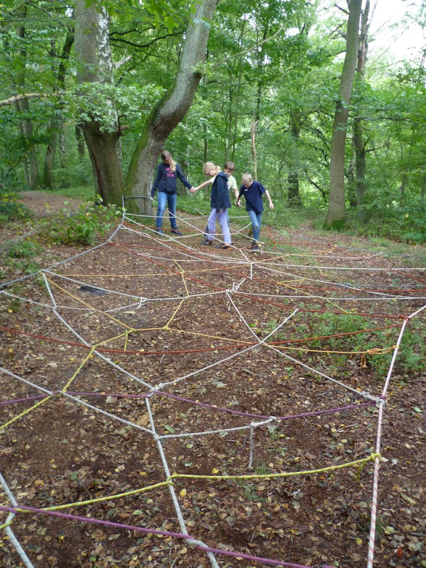 Ca. 30 cm über dem Boden ist eine Spinnennetz aus Seilen, das 4 Kinder überwinden ohne ein Seil zu berühren.